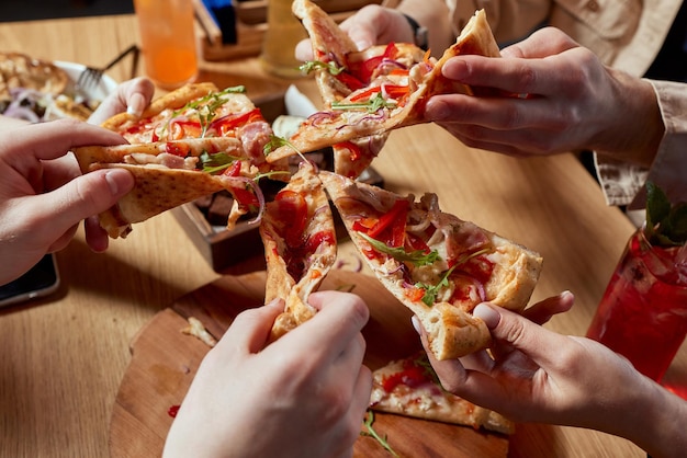 Image d'amis adolescents en train de prendre des tranches de pizza à la main