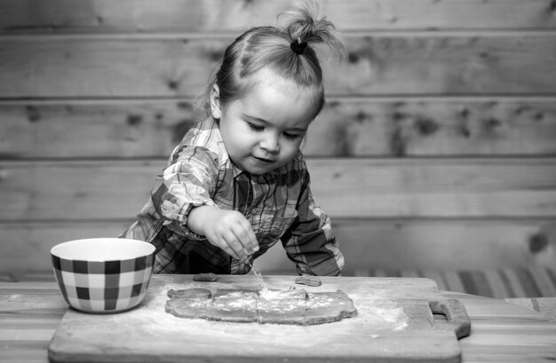 Image amusante du bébé chef jouant avec de la farine sur le fond de la cuisine en bois adorable petit cuisine maison