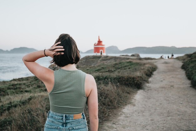 Image arrière d'un jeune randonneur voyageur sac à dos lors d'un magnifique scénario de littoral au coucher du soleil, concept de voyageur hipster, paysage de beauté. Copiez l'espace pour le texte. Mouvement et liberté, vie nomade.