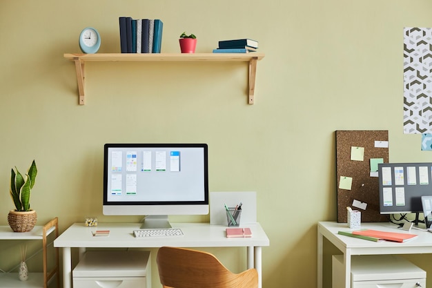 Image d'arrière-plan d'une configuration de bureau minimale avec écran d'ordinateur et tableaux de planification contre le jaune pastel