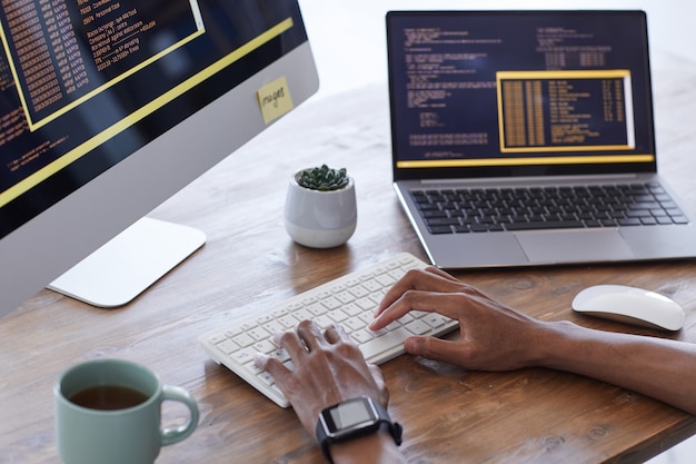 Image d'arrière-plan des mains mâles tapant sur le clavier tout en travaillant sur le code informatique dans le studio de développement informatique, copy space