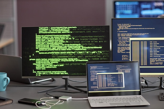 Photo image d'arrière-plan de plusieurs écrans d'ordinateur avec des lignes de code vertes sur le lieu de travail