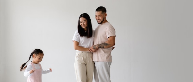 Photo image d'une bannière de jeunes parents asiatiques souriants se tenant par la main pendant que leur petite fille est isolée sur grey