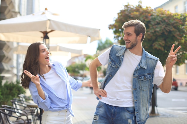 Image d'un beau couple heureux en vêtements d'été souriant et se tenant la main en marchant dans la rue de la ville.