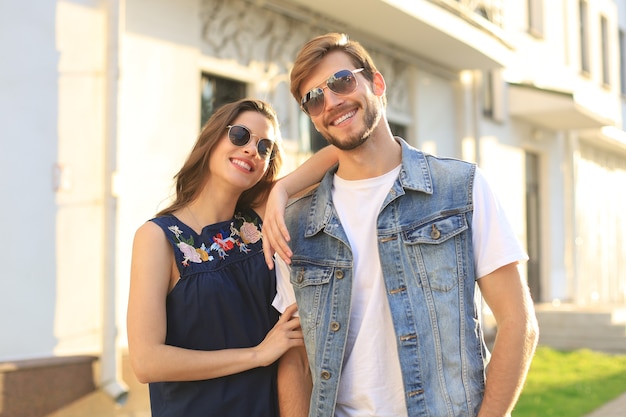 Image d'un beau couple heureux en vêtements d'été souriant et se tenant la main en marchant dans la rue de la ville.