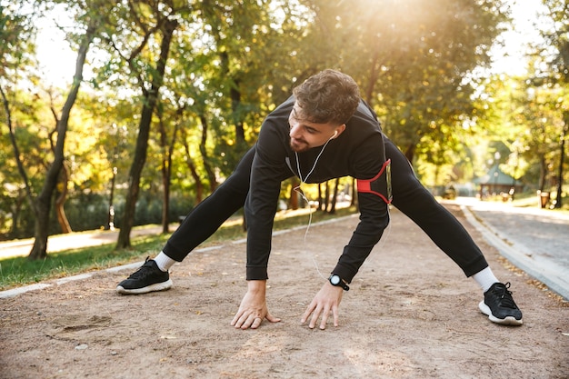 Image de beau jeune coureur de fitness sports homme à l'extérieur dans le parc faire des exercices.