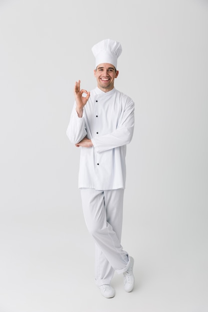 Image de beau jeune homme chef à l'intérieur isolé sur fond de mur blanc.