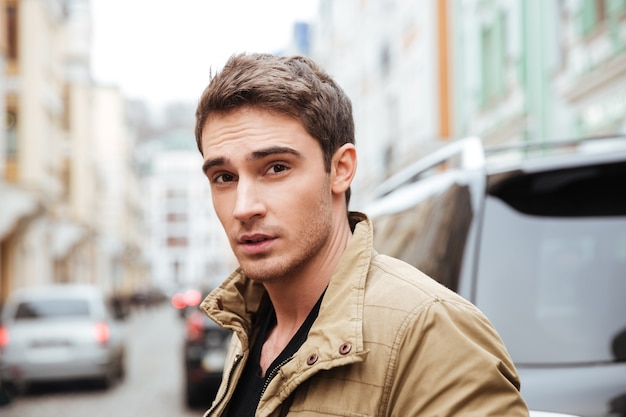 Image de beau jeune homme marchant dans la rue et regardant la caméra.