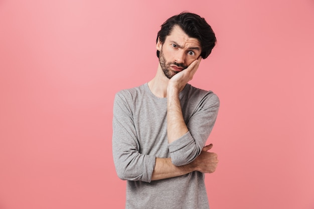 Image d'un beau jeune homme pensant sur un mur rose.