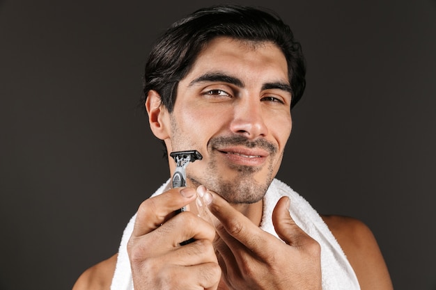 Image d'un beau jeune homme souriant isolé avec une serviette à raser.