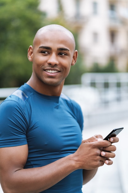 Image d'un beau jeune homme sportif fort à l'extérieur à l'aide d'un chat sur téléphone portable.