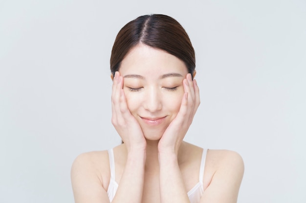 Image de beauté au sol dos blanc / femme asiatique touchant son visage