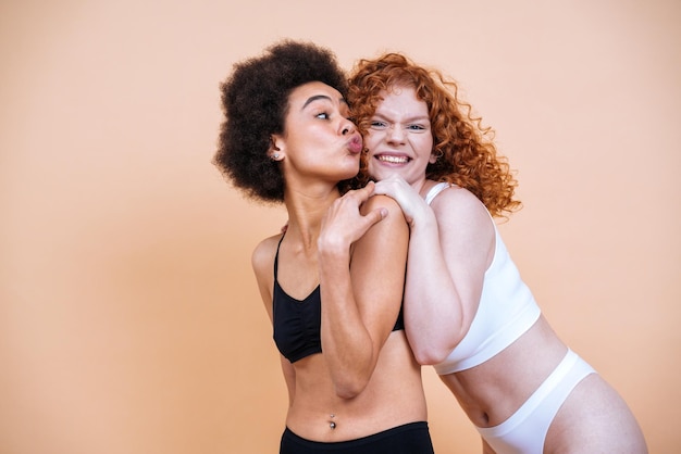 Image de beauté de deux jeunes femmes avec une peau et un corps différents posant en studio pour une séance photo positive du corps. Modèles féminins mixtes en lingerie sur fond coloré