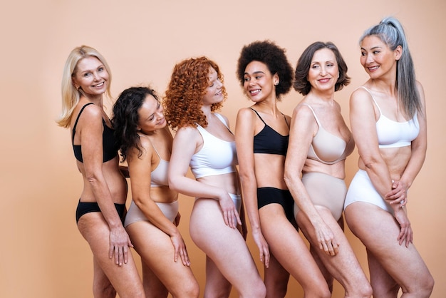 Image de beauté d'un groupe de femmes d'âge, de peau et de corps différents posant en studio pour une séance photo positive du corps. Modèles féminins mixtes en lingerie sur fond coloré