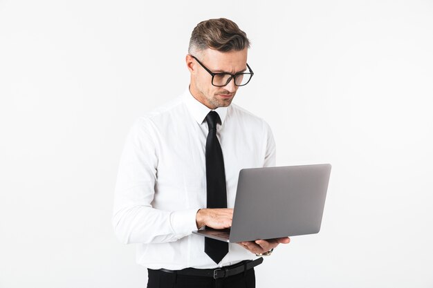 Image d'un bel homme d'affaires isolé sur un mur blanc à l'aide d'un ordinateur portable.