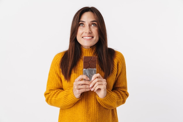 Image de belle femme adulte brune souriante et tenant une barre de chocolat isolée sur blanc