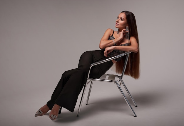 Image d'une belle femme élégante assise sur une chaise dans le studio sur un fond blanc