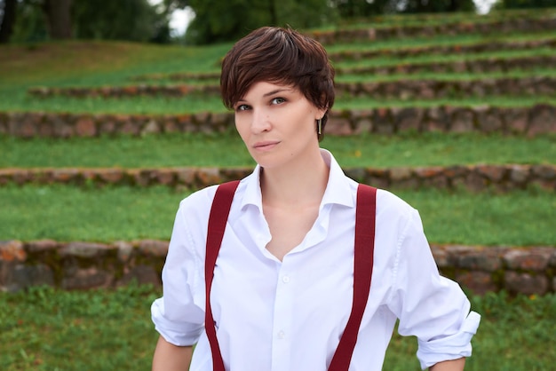 Image d'une belle femme élégante dans une chemise blanche, un pantalon noir et des bretelles rouges Le concept de style et de mode