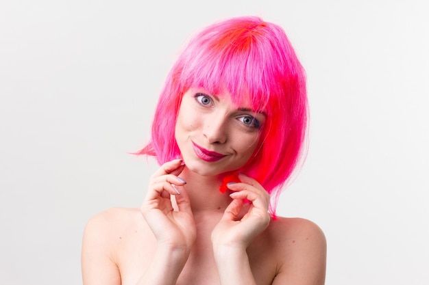 Image d'une belle femme excitée en perruque riant tout en posant avec des bonbons isolés sur fond rose
