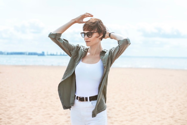 Image d'une belle femme sur la plage du golfe de Finlande à Saint-Pétersbourg. Temps venteux. Bonheur, liberté et insouciance. Notion de tourisme