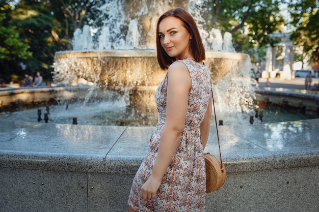 Image d'une belle femme souriante et regardant ailleurs, pendant ses vacances. Jolie femme marchant dans la rue de la ville, se relaxant par temps ensoleillé, sur fond de mer ou de parc avec espace de copie. Mode de vie