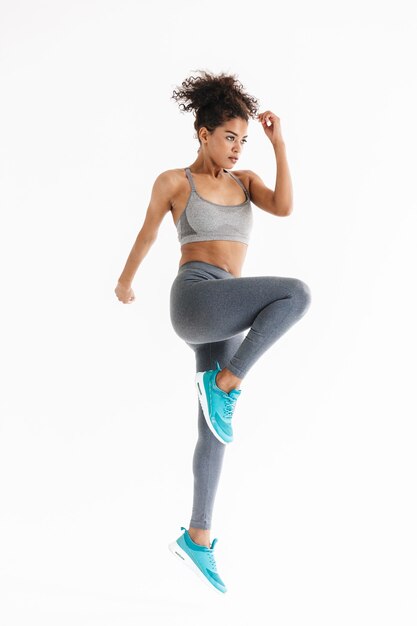 Photo image d'une belle jeune femme africaine de remise en forme sportive plus forte et étonnante faire des exercices isolés sur un mur blanc.