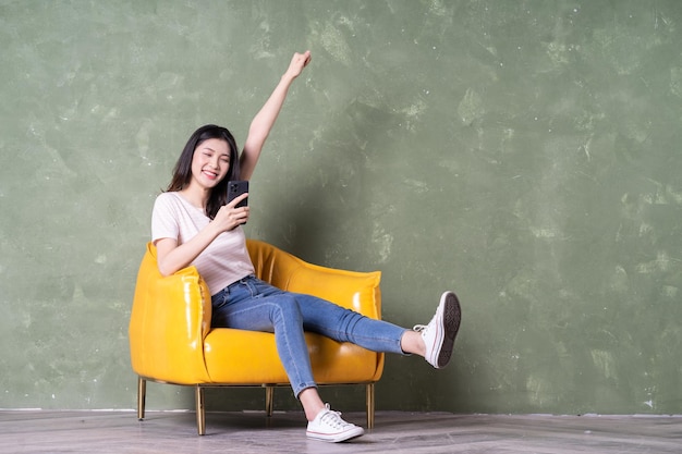 Image de la belle jeune femme asiatique assise sur un fauteuil jaune