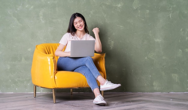 Image de la belle jeune femme asiatique assise sur un fauteuil jaune