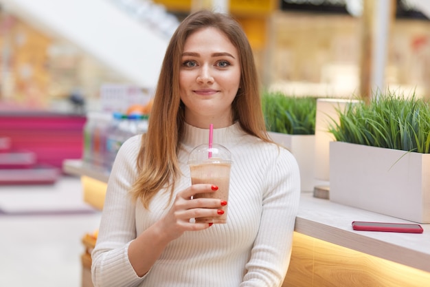 Image de la belle jeune femme est assise dans un café avec cocktail