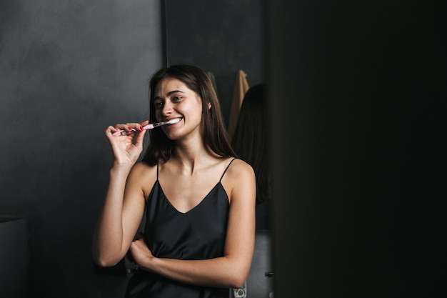 Image d'une belle jeune femme heureuse dans la salle de bain se brosser les dents.