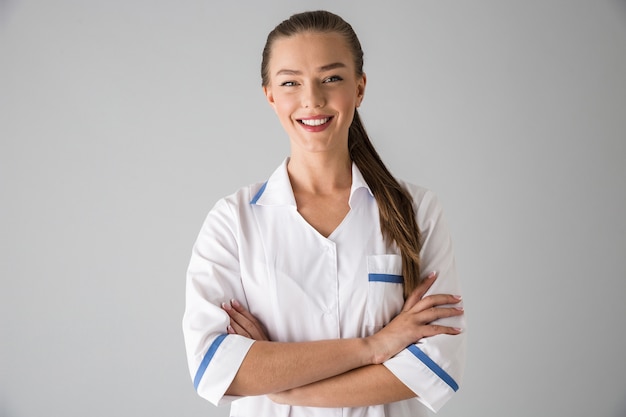 Image d'une belle jeune femme médecin cosmétologue isolé sur mur gris.