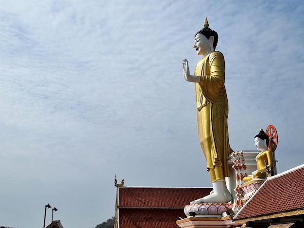 L'image de Bouddha dans la posture de bénédiction donnant sur un nuage dans le fond de ciel bleu