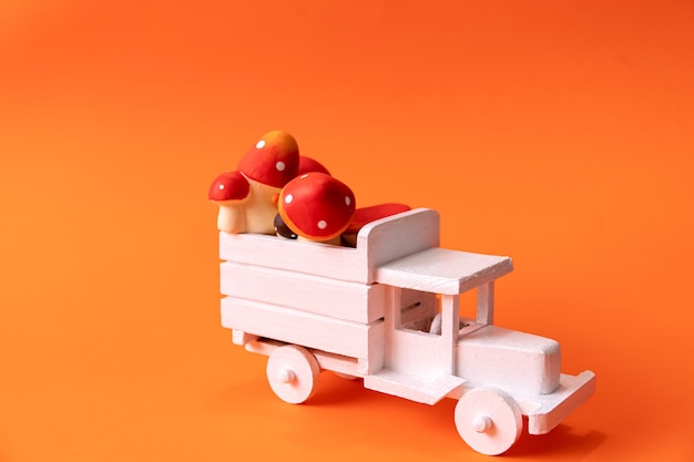 Image d'un camion blanc en bois sur fond orange avec des champignons rouges