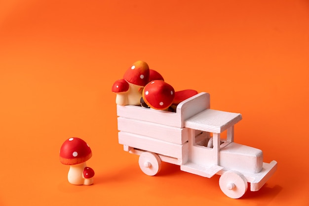 Image d'un camion blanc en bois sur fond orange avec des champignons rouges