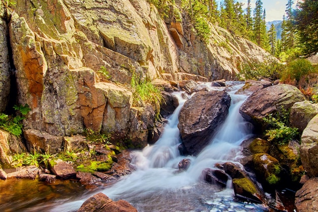 Image de cascade à travers de gros rochers dans les montagnes avec des rochers de lichen