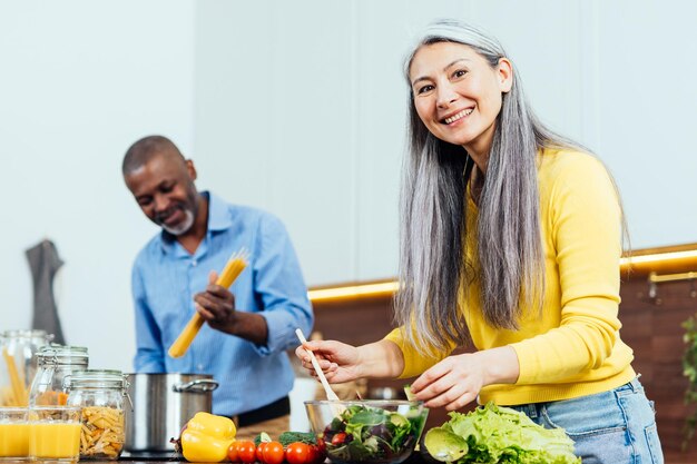 Photo image cinématographique d'un couple senior multiethnique préparant de la nourriture dans la cuisine intérieur moments de style de vie à la maison concept sur l'ancienneté et les relations