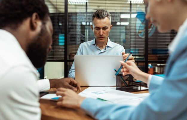 Image cinématographique d'employés d'une équipe commerciale multiethnique travaillant ensemble dans un bureau moderne