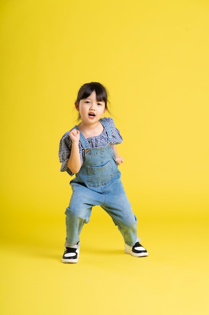 Image complète du corps d'une belle petite fille asiatique sur fond jaune