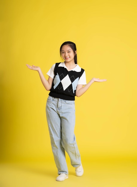 image complète du corps d'une fille asiatique debout et posant sur fond jaune