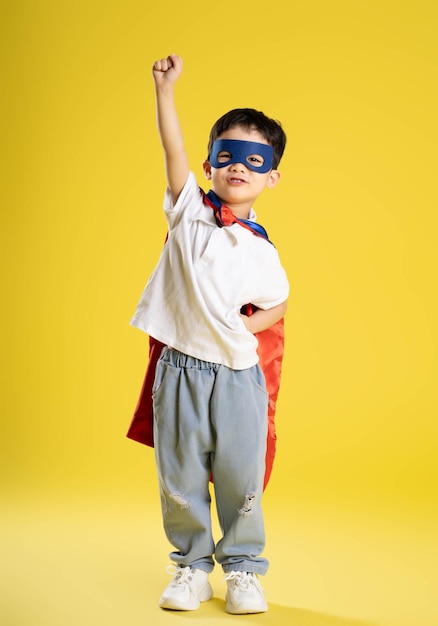 Image complète du corps d'un garçon portant une chemise de super-héros posant sur un fond jaune