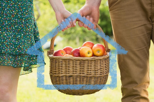 Image composée du panier des pommes étant porté par un jeune couple