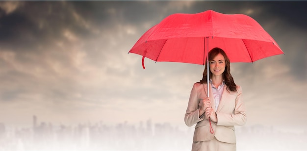 Image composée de femme d'affaires attirante tenant le parapluie rouge