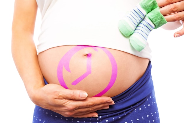 Image composée de femme enceinte tenant des chaussures de bébé au-dessus de la bosse