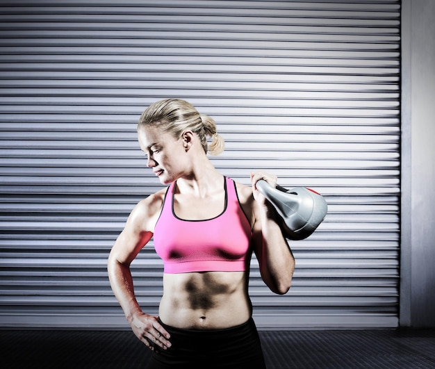 Image composée de femme musculaire soulevant le kettlebell lourd