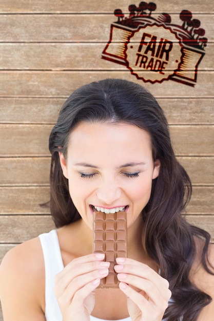 Image composée de jolie brune mangeant la barre de chocolat