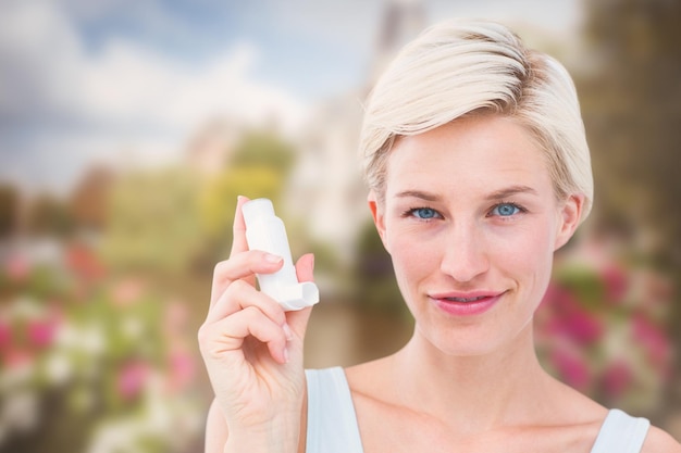 Image composée de jolie femme tenant l'inhalateur souriant à l'appareil-photo