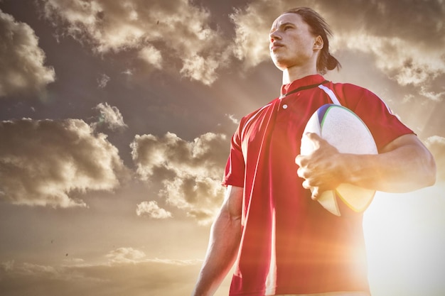 Image composée de joueur de rugby tenant le football au champ