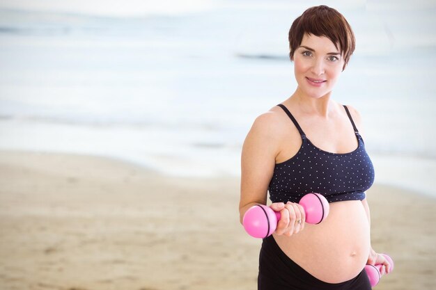 Image composée de portrait de femme enceinte soulevant des haltères