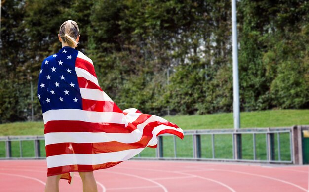 Image composée de vue arrière de femme sportive tenant un drapeau américain