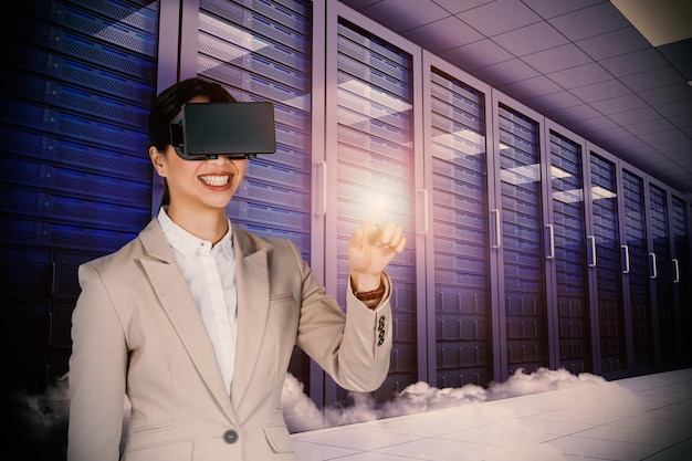 Image composite de femme d'affaires souriante pointant tout en portant des lunettes vidéo virtuelles